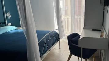 Ein Schlafzimmer mit einem Bett, einem Schreibtisch, einem Sessel und einem Fernseher.