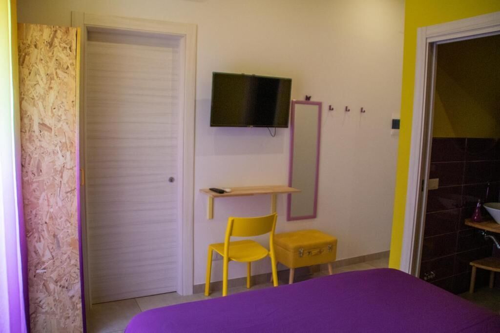 A room with a bed, a desk, a chair, a television, and a mirror.