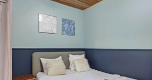 A bedroom with a bed, two pillows, a wooden headboard, and two framed artworks on the wall. - Elégant 2 pièces proche du Marais (Paris)