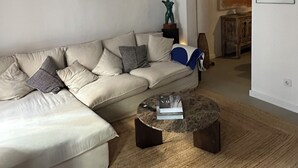 Un saló amb un sofà beix, una taula de centre rodona i una catifa teixida.