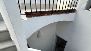 Una escala amb parets blanques i barana metàl·lica, que condueix a un badiu amb una porta.