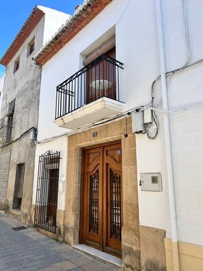 A two-story building with a balcony, a wooden door with a metal gate, and a visible number '19' on the wall. - Perfect 5-bedroom house with AC in lovely Xàbia (Xàbia)
