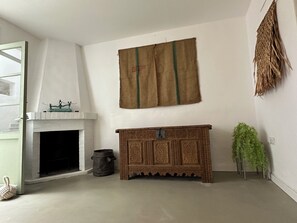Ein Zimmer mit einem weißen Kamin, einem rustikalen Holzschrank und einer grünen Pflanze.