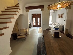 Ein geräumiger Wohnbereich mit einer Holztreppe, einem Esstisch mit Stühlen und einem Sofa.