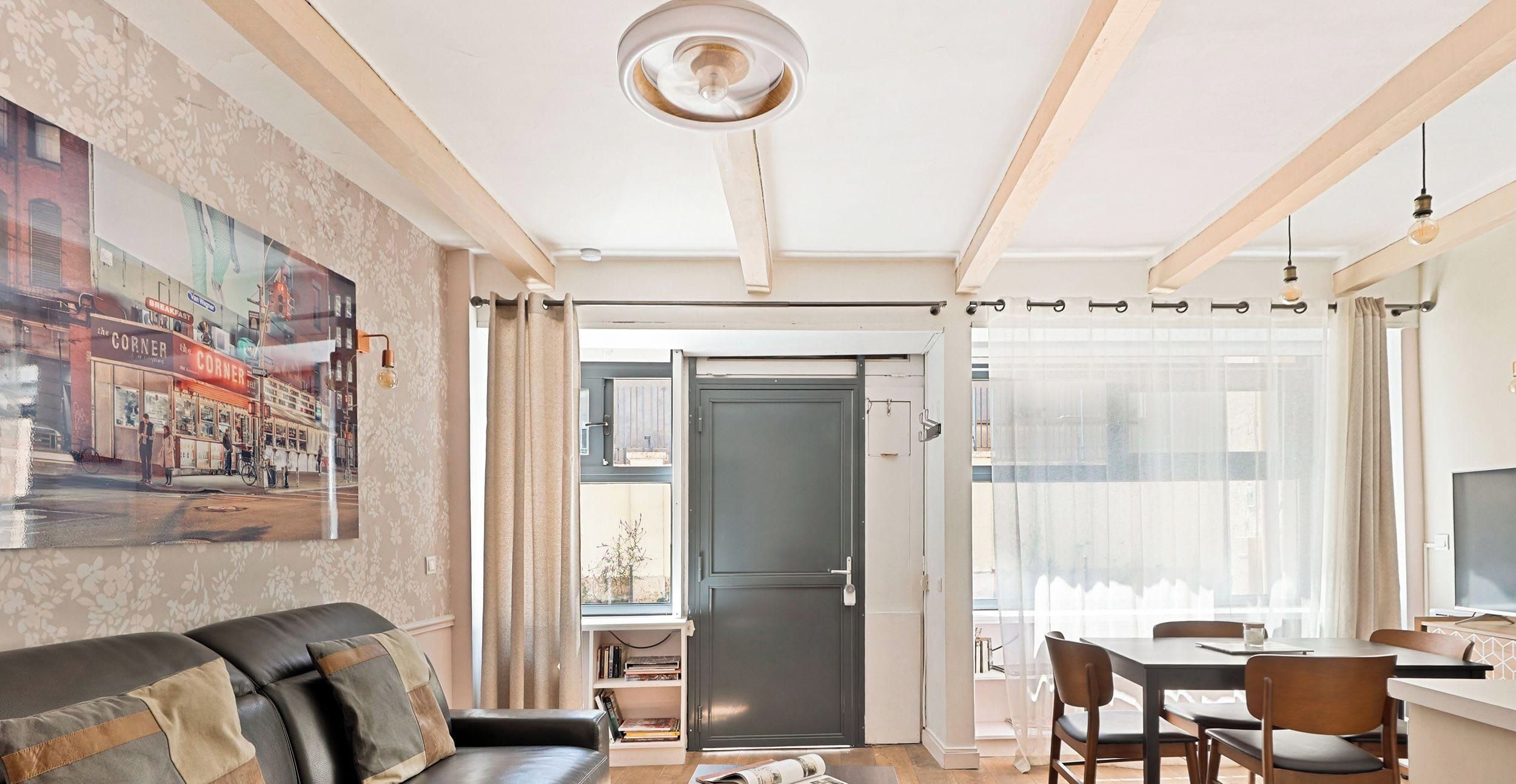 Un soggiorno con un divano, un tavolo da pranzo con sedie, una televisione e una porta che dà su un balcone.