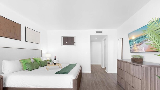 Een moderne slaapkamer met een bed, nachtkastje, lamp en kunstwerk.