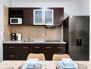 A modern kitchen with dark cabinets, a stainless steel refrigerator, a microwave, and a coffee maker. - Quiet 2BR Haven with Worspace Surrounded by Nature (Playa del Carmen)