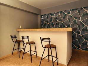 A bar area with a counter and three bar stools. - Quiet 2BR Haven with Worspace Surrounded by Nature (Playa del Carmen)