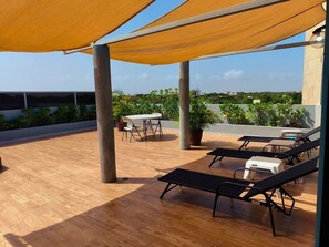 Un patio exterior con piso de madera, una mesa con sillas y sillones de descanso.