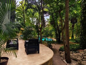 A circular outdoor seating area with a concrete edge, surrounded by lush greenery and trees. - Quiet 2BR Haven with Worspace Surrounded by Nature (Playa del Carmen)
