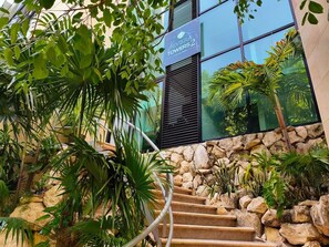 Eine Treppe mit Steinmauer und Bepflanzung, die zu einem Gebäude führt, an dem ein Schild 'RIVIERA TOWERS 2' angebracht ist.