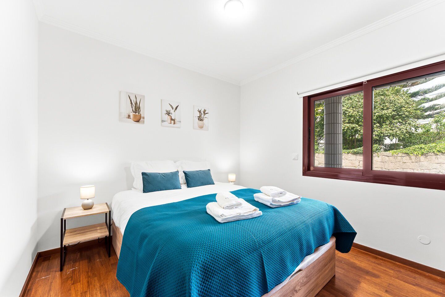 A bedroom with a bed, bedside tables, a window, and wall art.