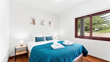 A bedroom with a bed, bedside tables, a window, and wall art.