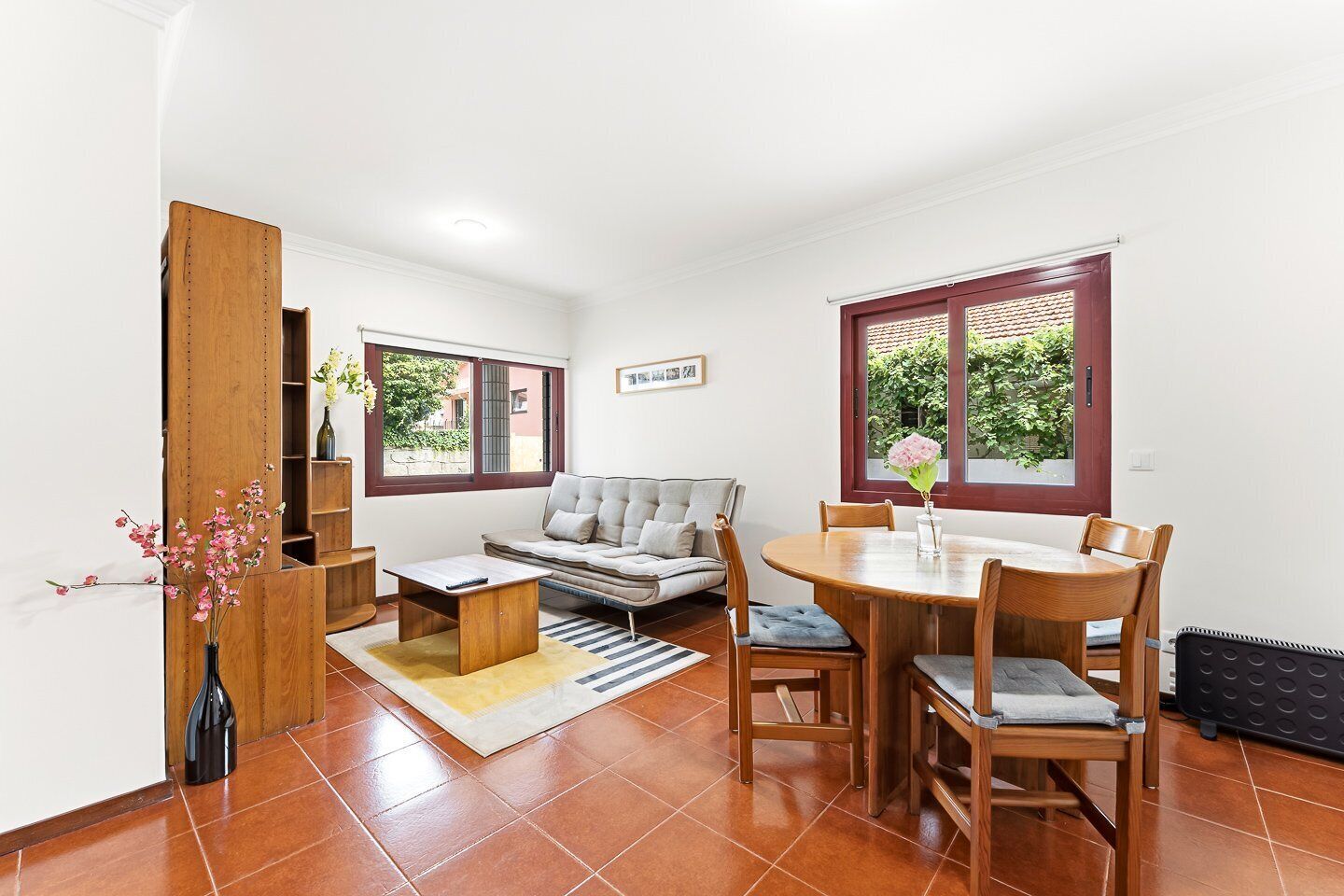 A compact living space with a sofa, dining table, chairs, a small coffee table, and a bookshelf.