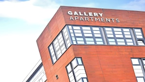En byggnad med skylten ”GALLERY APARTMENTS”, vilket visar att det är ett bostadskomplex.