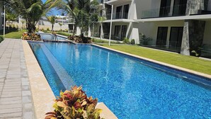A swimming pool with a tiled edge, surrounded by a paved walkway. - Eden Tropical new 1BR Condo, Walk to Beach ,pool (Punta Cana)