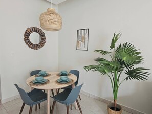 A dining area with a round table, blue chairs, and a large potted plant. - Eden Tropical new 1BR Condo, Walk to Beach ,pool (Punta Cana)
