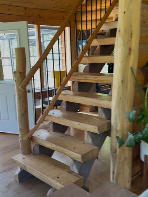 A wooden staircase with a handrail and a door at the bottom.