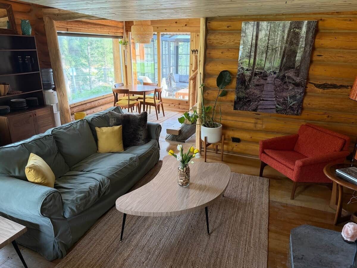En mysig stuga med en soffa, ett soffbord och en röd fåtölj.