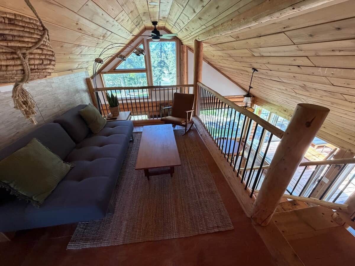 L’intérieur d’un chalet confortable, avec un canapé, une petite table et une vue par la fenêtre.