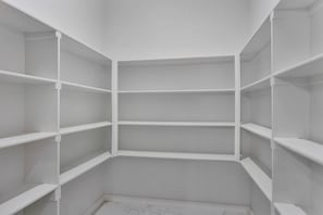 Ein Eckschrank mit weißen Regaleinheiten und Fliesenboden.