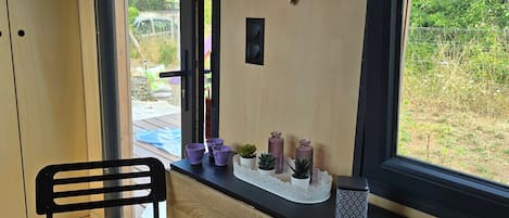 A room with a wooden desk, two chairs, a window with a view of greenery, and decorative butterfly wall art.