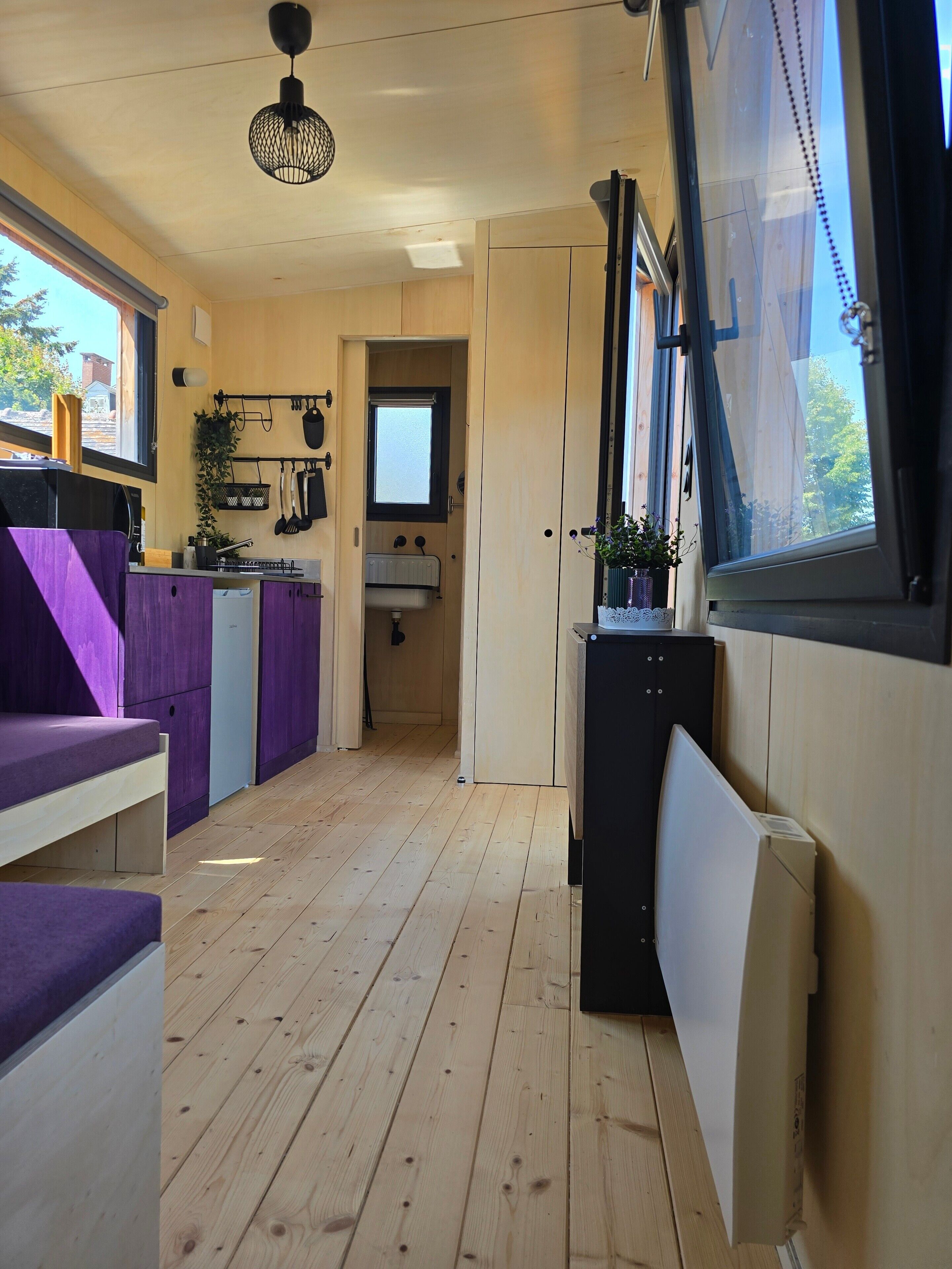 Una cucina compatta con pavimento in legno, una panca integrata e una finestra che dà sull'esterno.