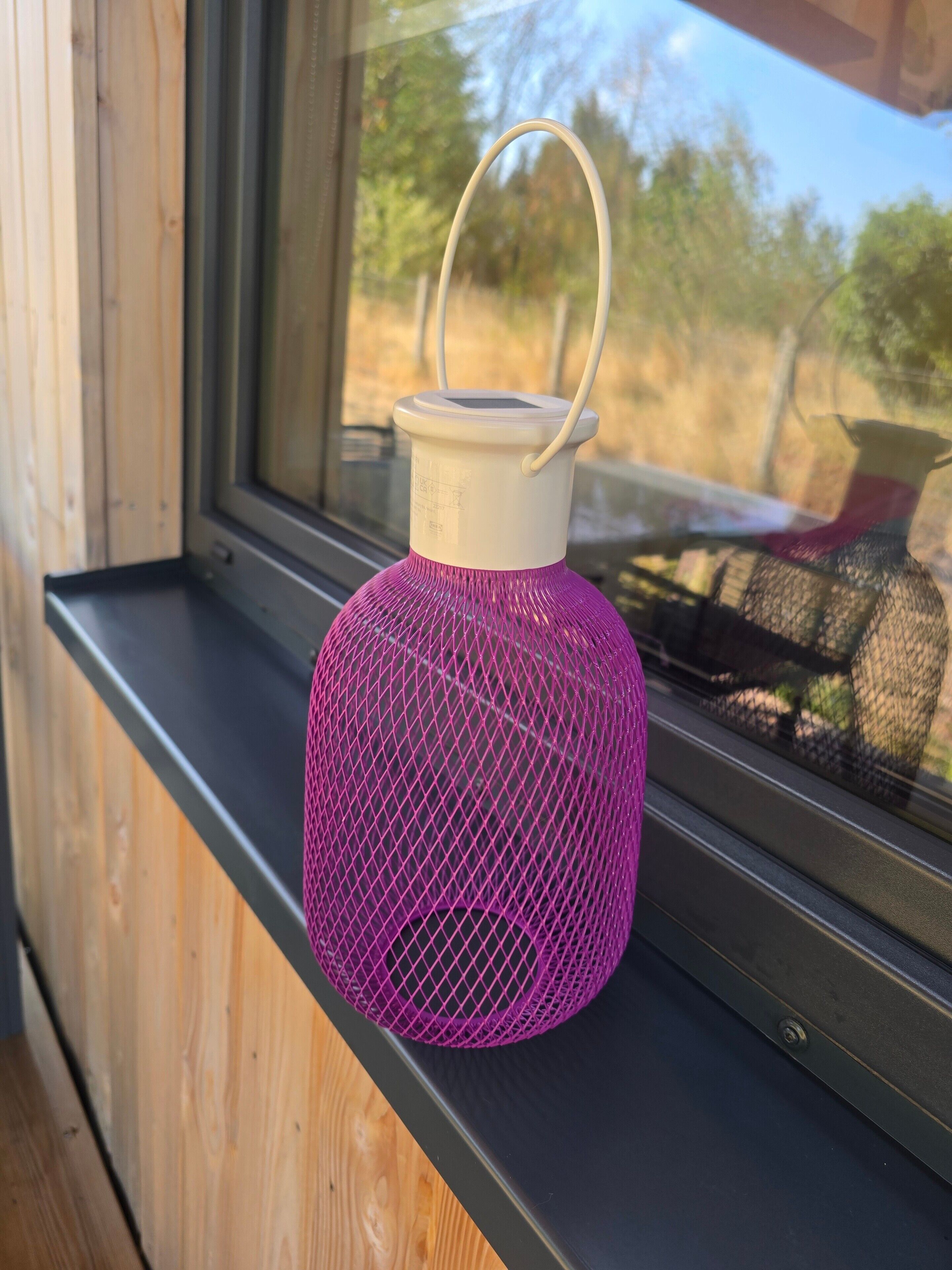 Eine violette Netzlaterne auf einem Fensterbrett.