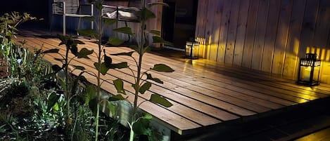 A wooden deck with a bench, a small table, and a potted plant.