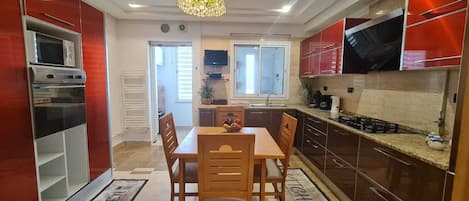 A compact kitchen with a dining area, equipped with a microwave, oven, and gas stove.