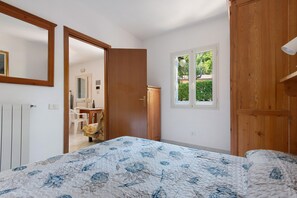 Ein Schlafzimmer mit einem Bett, einem Fenster und einer Tür zu einem Badezimmer.