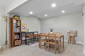 Ein Essbereich mit Holztisch und Stühlen, einem Bücherregal und einer Stehlampe.