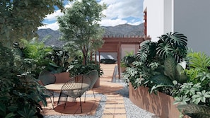 Un patio con mesa y sillas, rodeado de plantas y vistas a montañas.