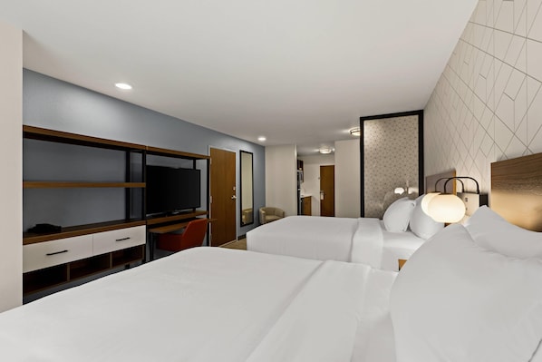 Una camera d'albergo con un letto, una televisione, una scrivania e un armadio.