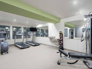 A gym with treadmills, a stationary bike, a bench press, and a wall-mounted medicine ball rack. - Woodspring Suites Rock Hill Charlotte (Rock Hill)