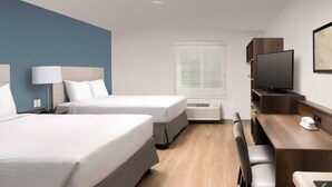 A hotel room with two beds, a desk, a chair, a television, and a window with blinds. - Woodspring Suites Rock Hill Charlotte (Rock Hill)