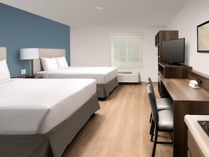 A hotel room with two beds, a desk, a chair, a television, and a window with blinds. - Woodspring Suites Rock Hill Charlotte (Rock Hill)