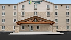 A hotel with a stone facade, multiple windows, and a central entrance with a wooden canopy. - Woodspring Suites Rock Hill Charlotte (Rock Hill)