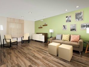 A modern living room with a sofa, armchairs, ottomans, a coffee table, and a side table with a lamp. - Woodspring Suites Rock Hill Charlotte (Rock Hill)