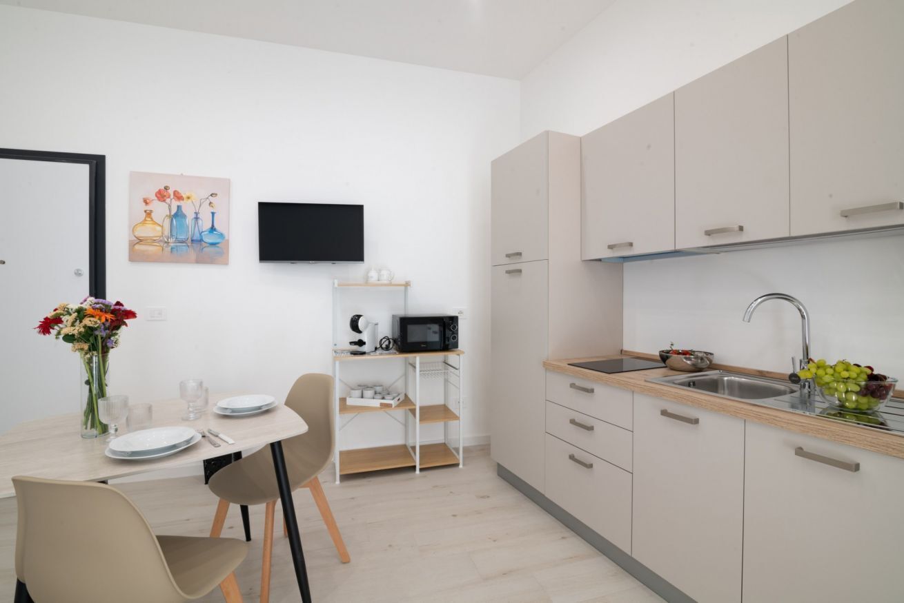 A modern kitchen with a built-in microwave, a sink, and a dining area with a table and chairs.
