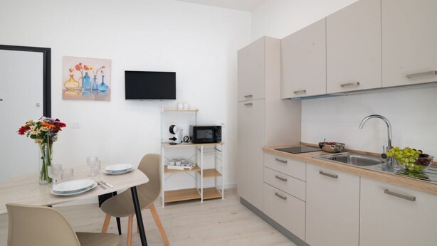 Eine moderne Küche mit eingebauter Mikrowelle, einer Spüle und einem Essbereich mit Tisch und Stühlen.