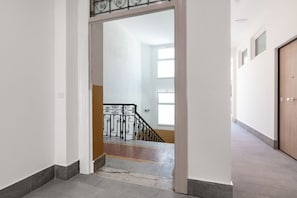 A hallway leading to a staircase with a metal railing. - Cozy 25 sqm studio apartment, for two guests, located on the second floor of a renovated historic building (no elevator). The property enjoys a strategic location just steps away from the Policlinico hospital, the Ballarò district, and the city center;  (Palermo)