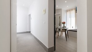 Ein modernes Hotelzimmer mit einem großen Spiegel, einem Essbereich mit Tisch und Stühlen und einer kleinen Sitzecke mit einer Bank.
