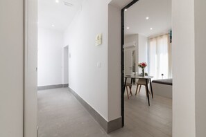 A modern hotel room with a large mirror, a dining area with a table and chairs, and a small seating area with a bench. - Cozy 25 sqm studio apartment, for two guests, located on the second floor of a renovated historic building (no elevator). The property enjoys a strategic location just steps away from the Policlinico hospital, the Ballarò district, and the city center;  (Palermo)