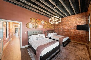 Ein Schlafzimmer mit zwei Betten, einer Ziegelwand und einer Decke mit sichtbaren Holzbalken.