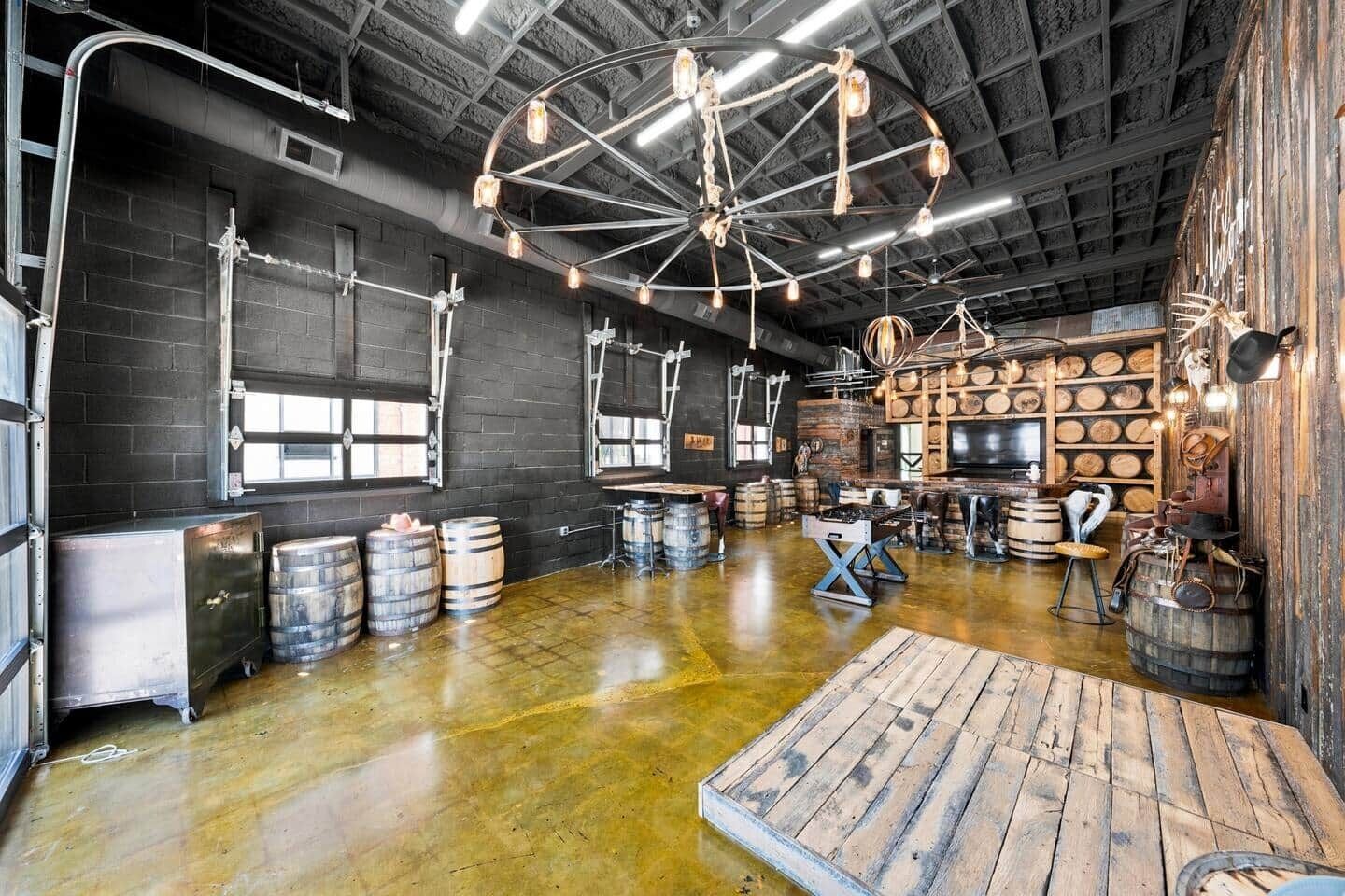 A spacious room with a polished concrete floor, wooden barrels, and a large wooden table.