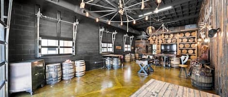 A spacious room with a polished concrete floor, wooden barrels, and a large wooden table.