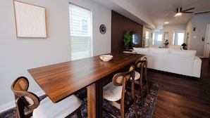 A modern dining area with a wooden table, four chairs, and a white sofa in the background.