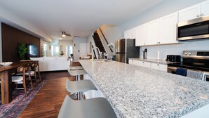 A modern kitchen with a long island, stainless steel appliances, and a dining area with bar stools.