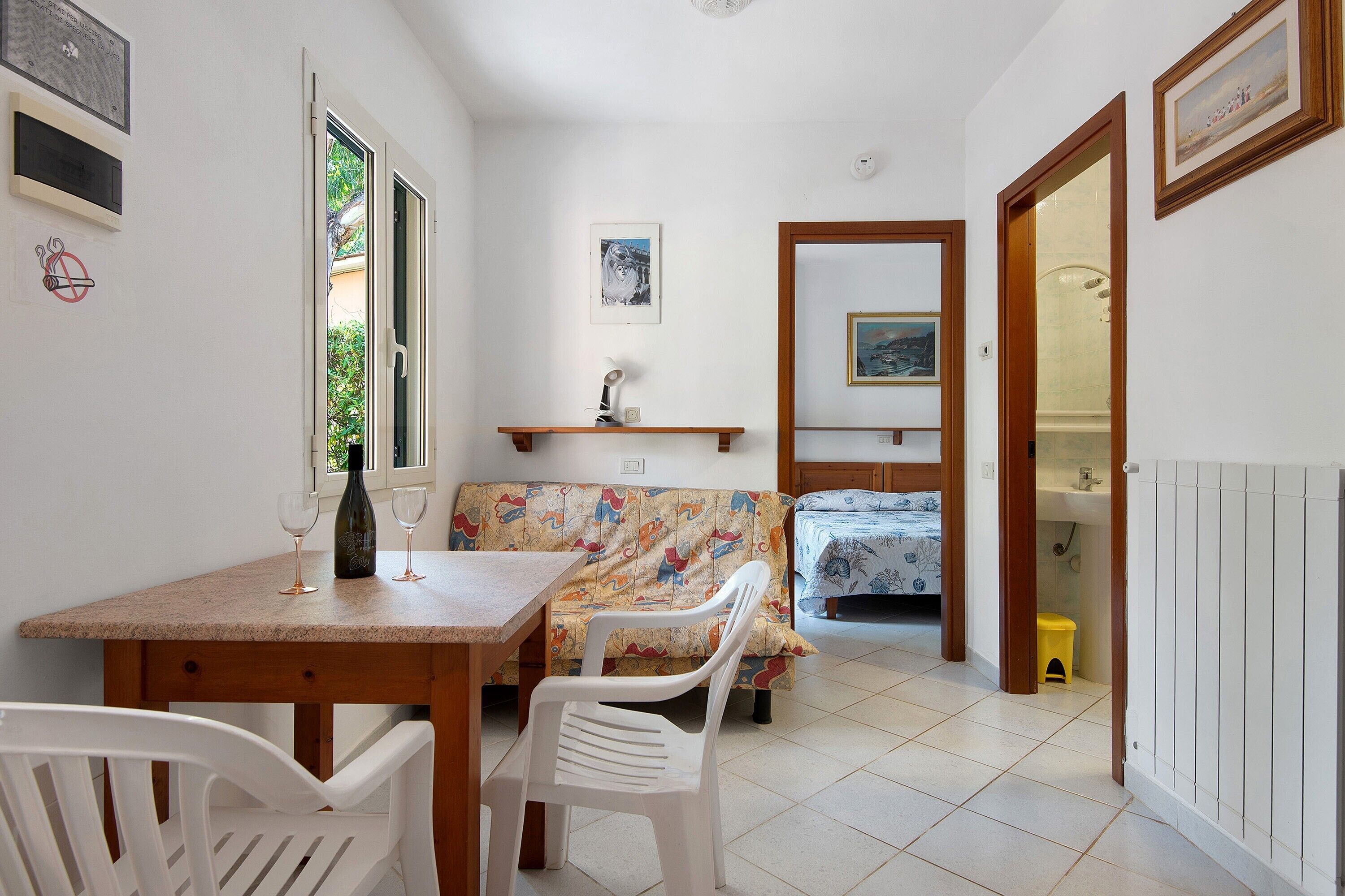Habitación compacta con mesa de comedor, sillas, sofá, cama y baño pequeño.
